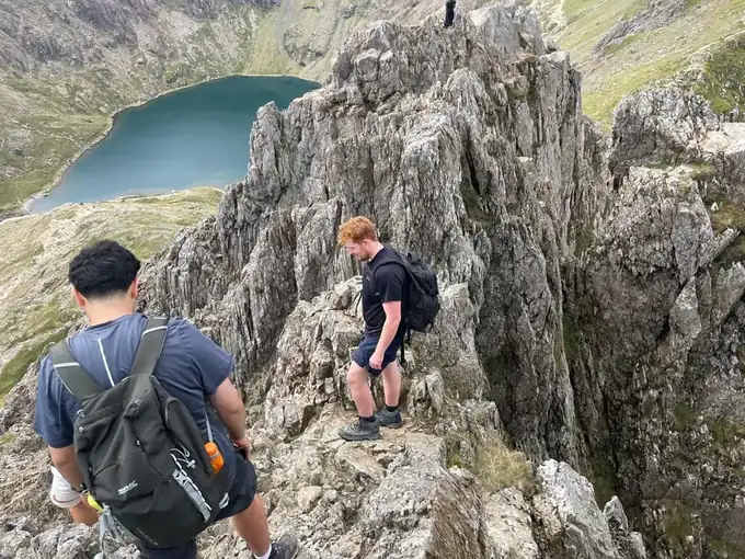 Walkers scrambling along a rocky ridge high on Yr Wyddfa